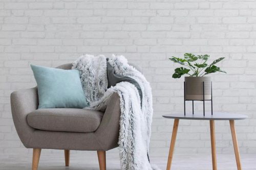 Weiße Vliestapeten in Steinoptik hinter einem Sessel