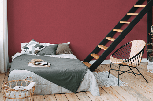 Einfarbige rote Tapete hinter einem Bett